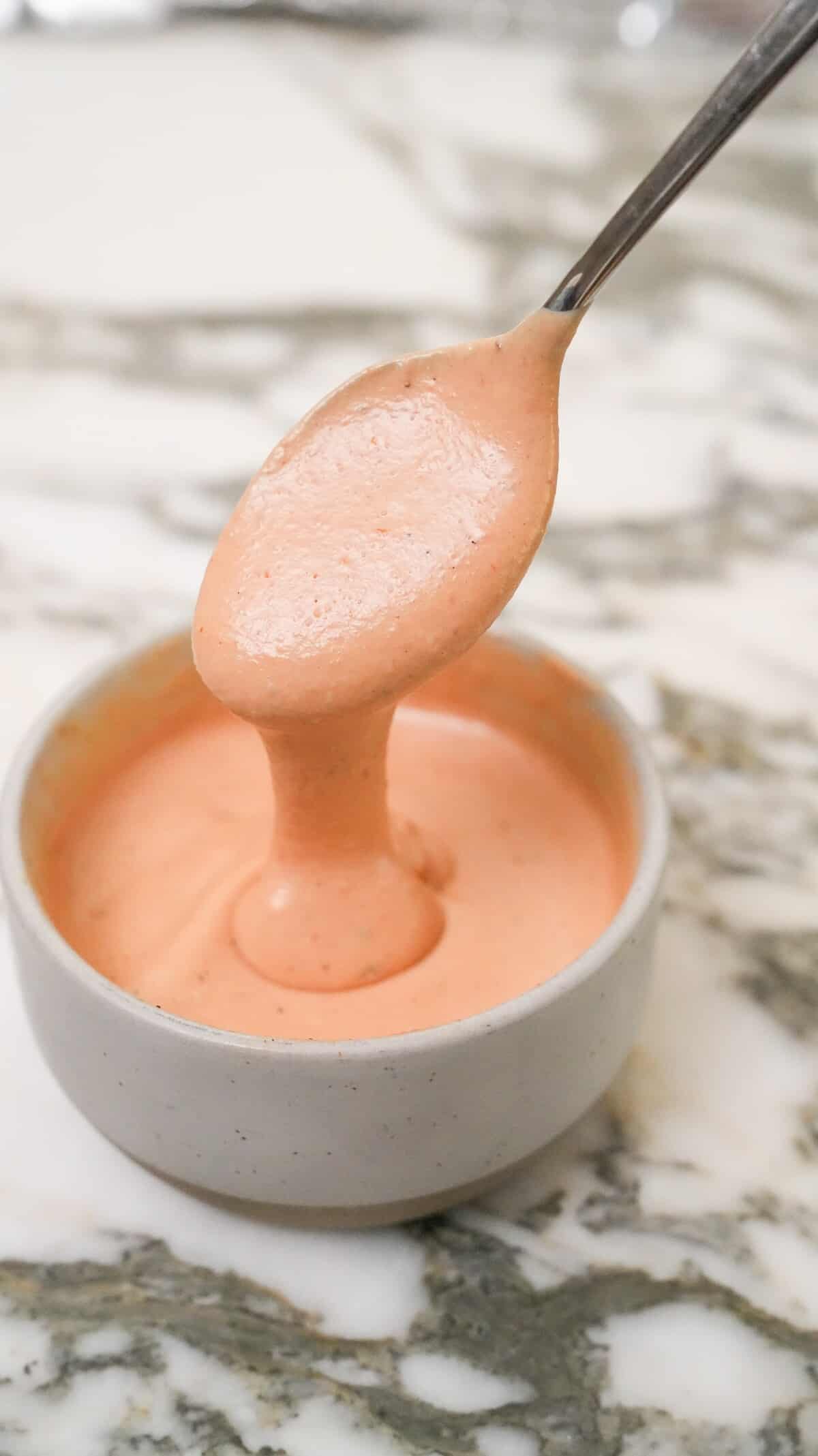 Raising Cane's sauce in a bowl with a spoon.