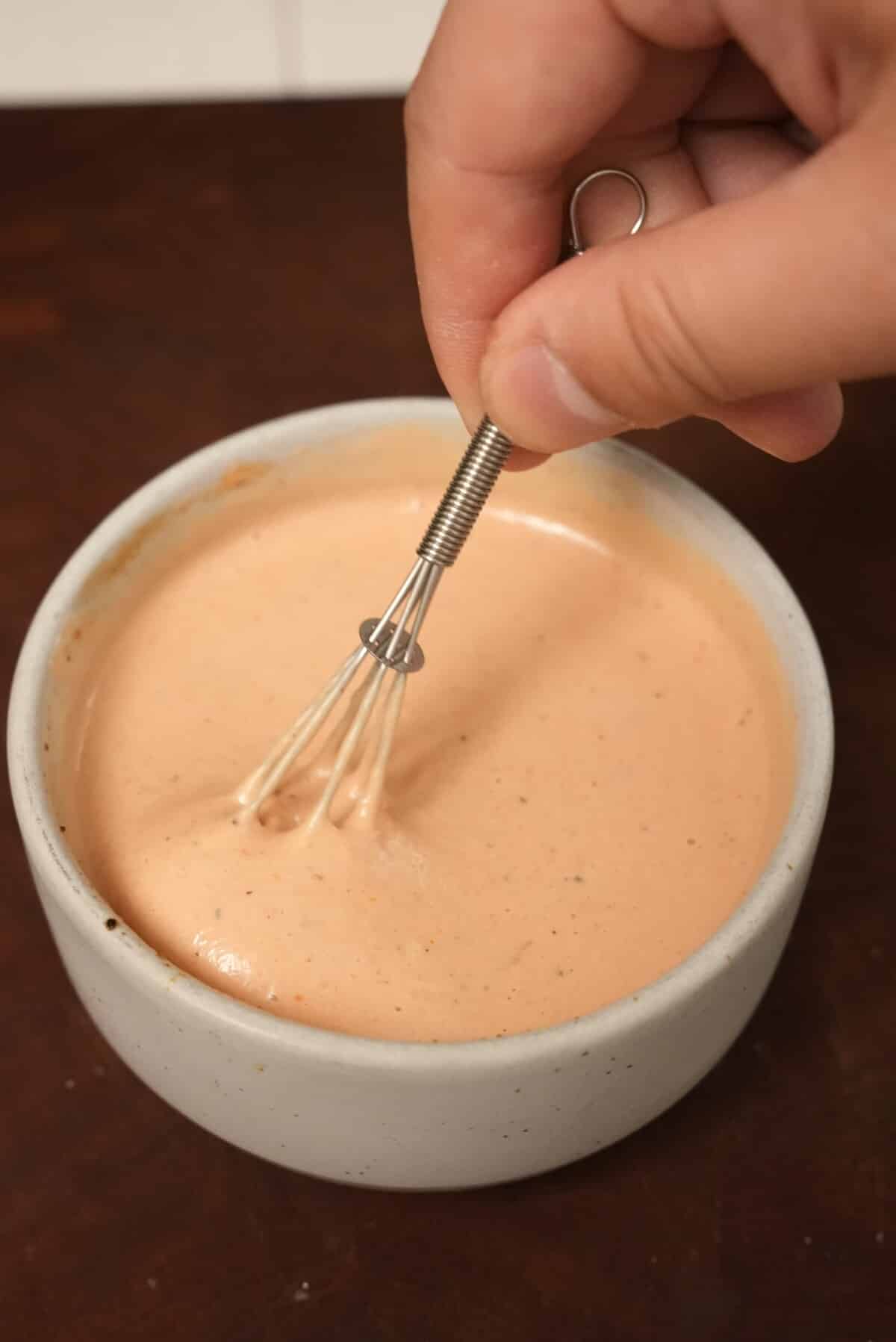 Mixing the sauce in a bowl with a whisk.