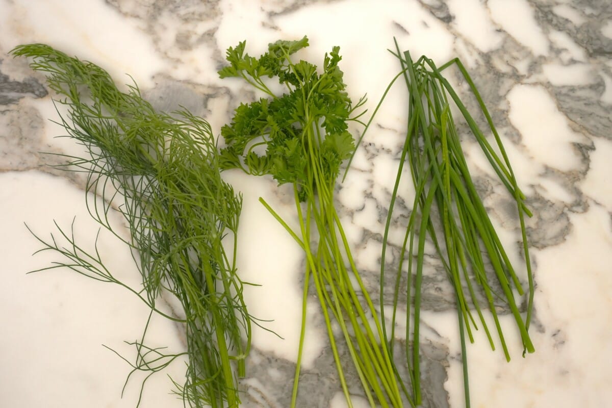 Fresh dill, fresh parsley, and fresh chives on a table.