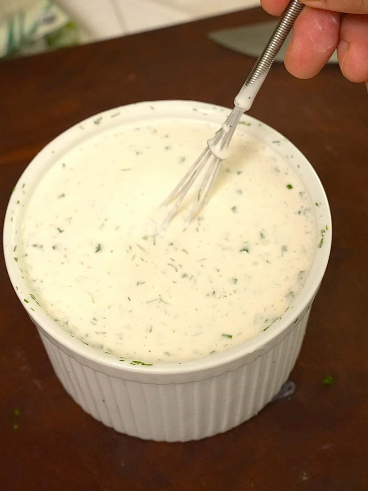 Mixing ranch dressing with a whisk.