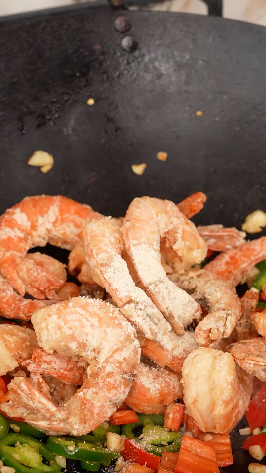 Spicy Salt added onto shrimp in a wok.