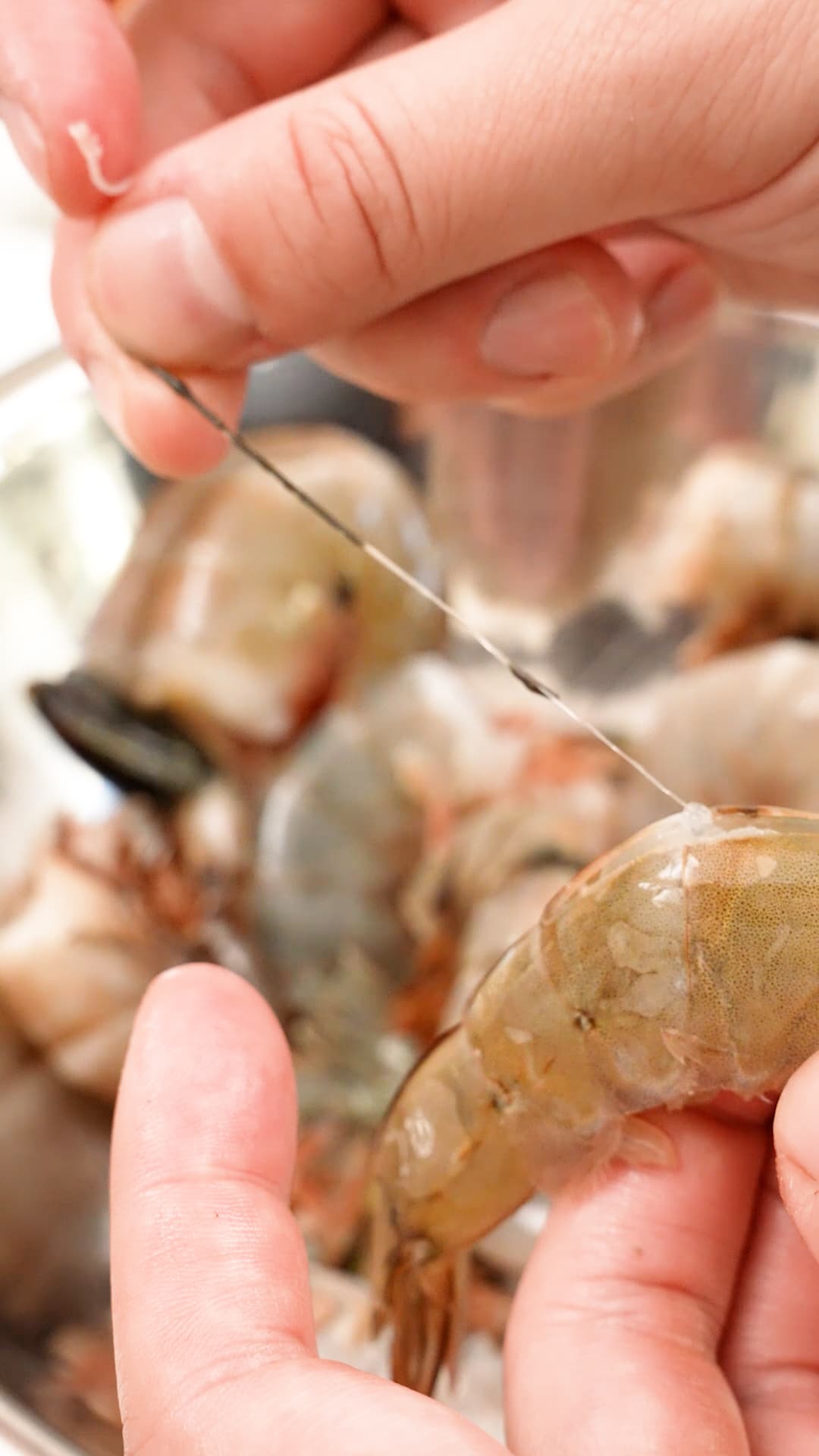 A shell on shrimp being deveined with two hands.