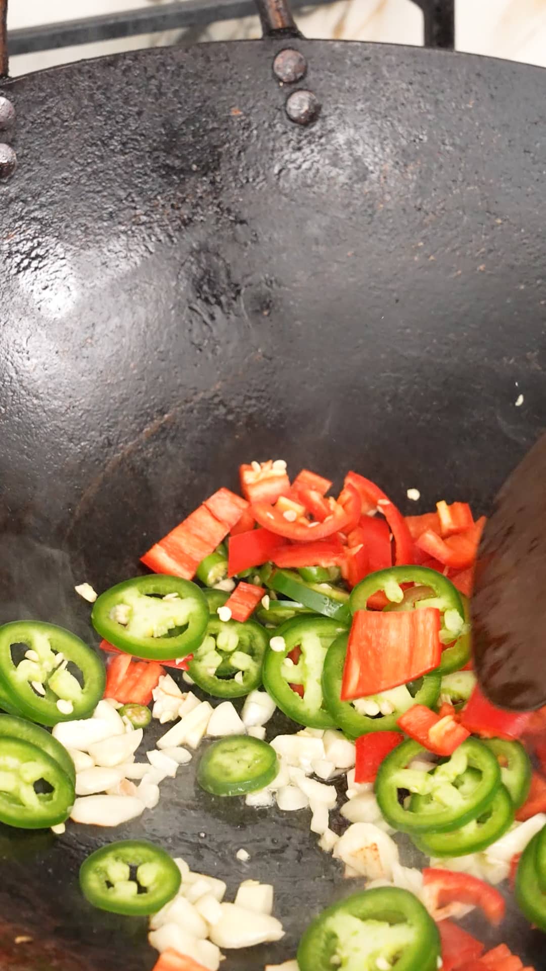 Aromatics being cooked in a wok.