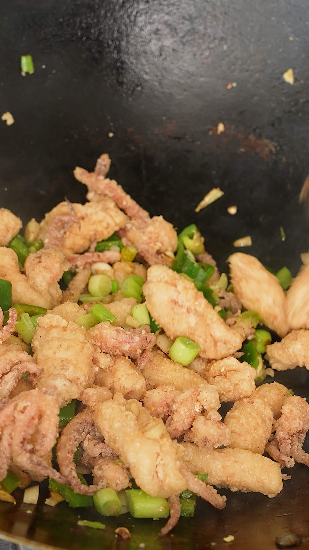 Salt and pepper squid tossed in a wok.