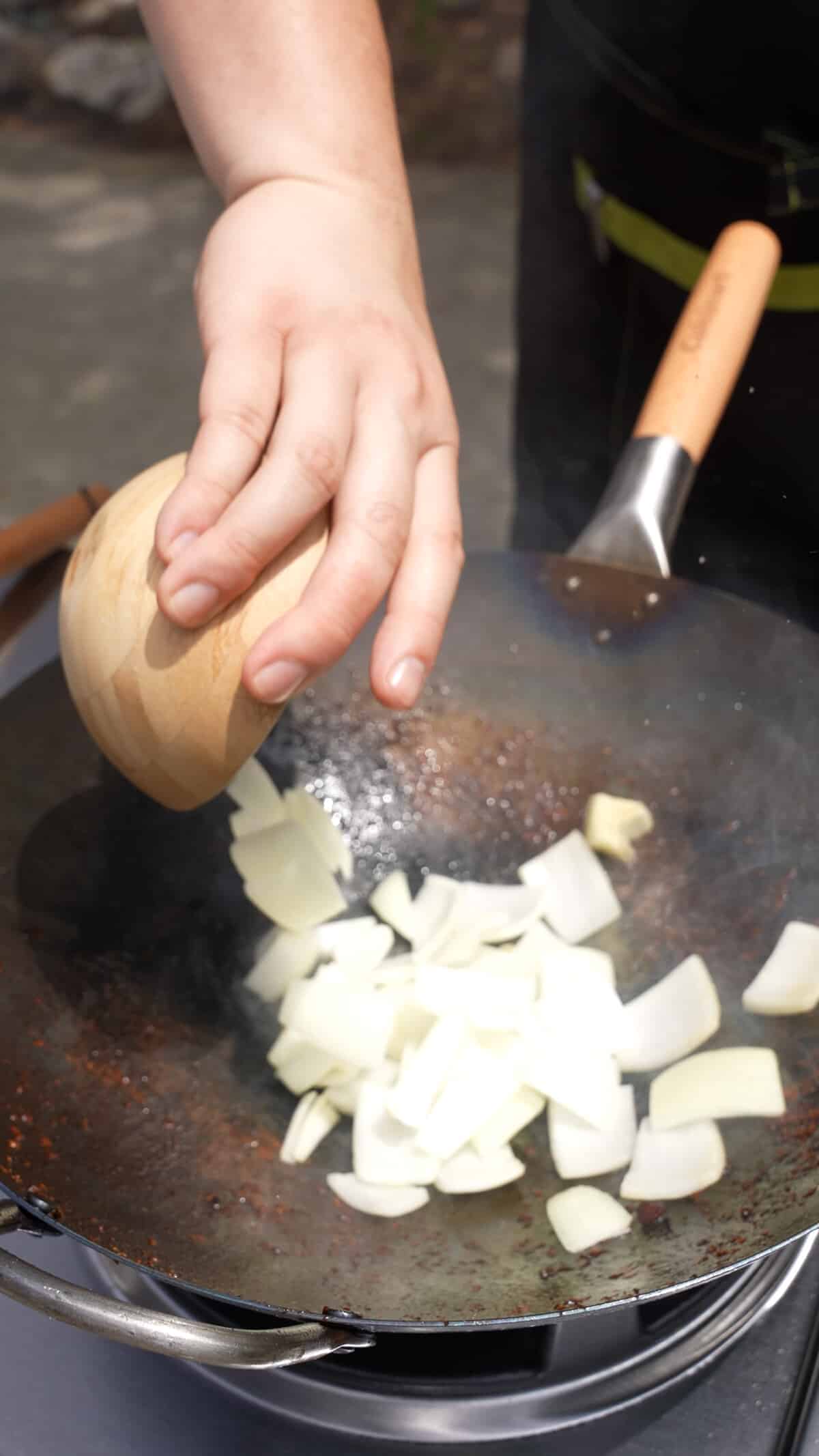 Adding onions to a hot wok.