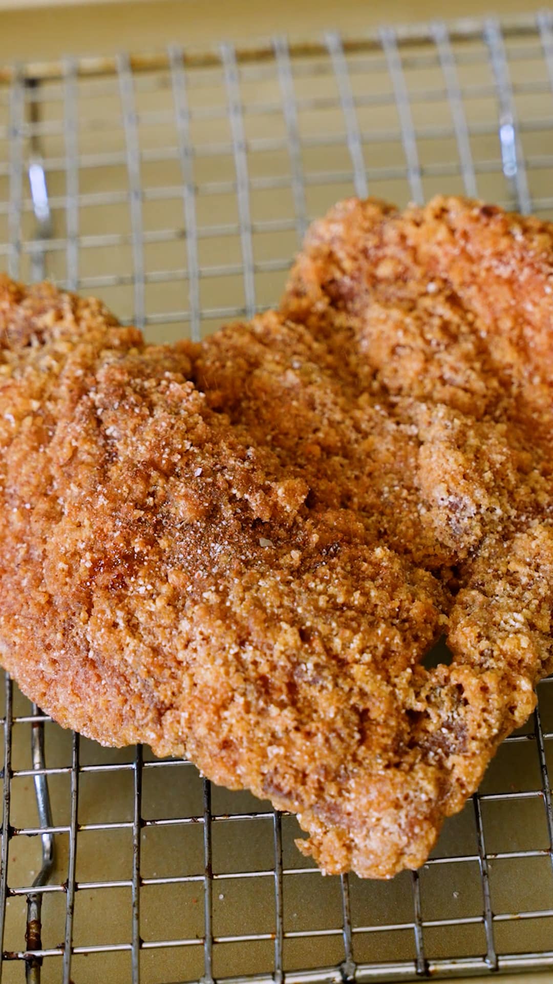 A fried chicken breast being seasoned with a Taiwanese chicken spice mixture.