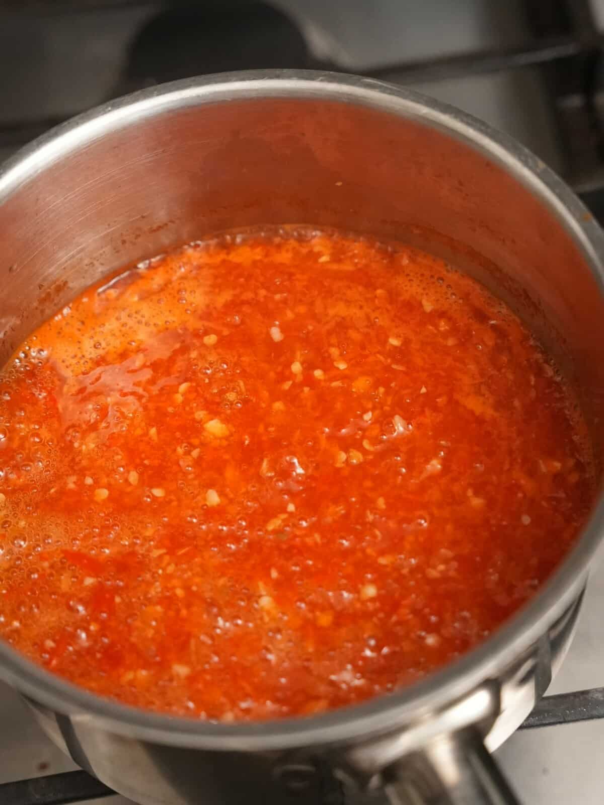 Thai sweet chili sauce simmering in a saucepan.