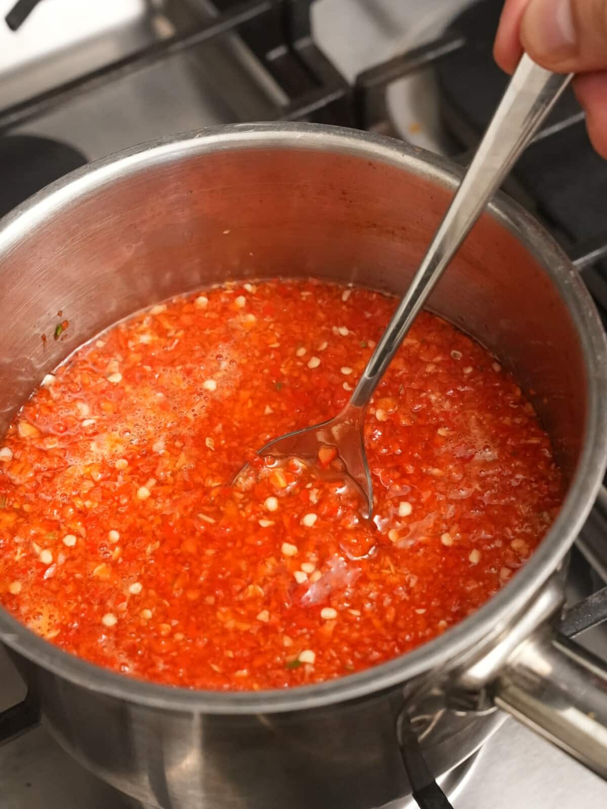 Stirring thai sweet chili sauce with a spoon.