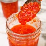 Cooked Sweet Thai Chili Sauce in a jar with a spoon.