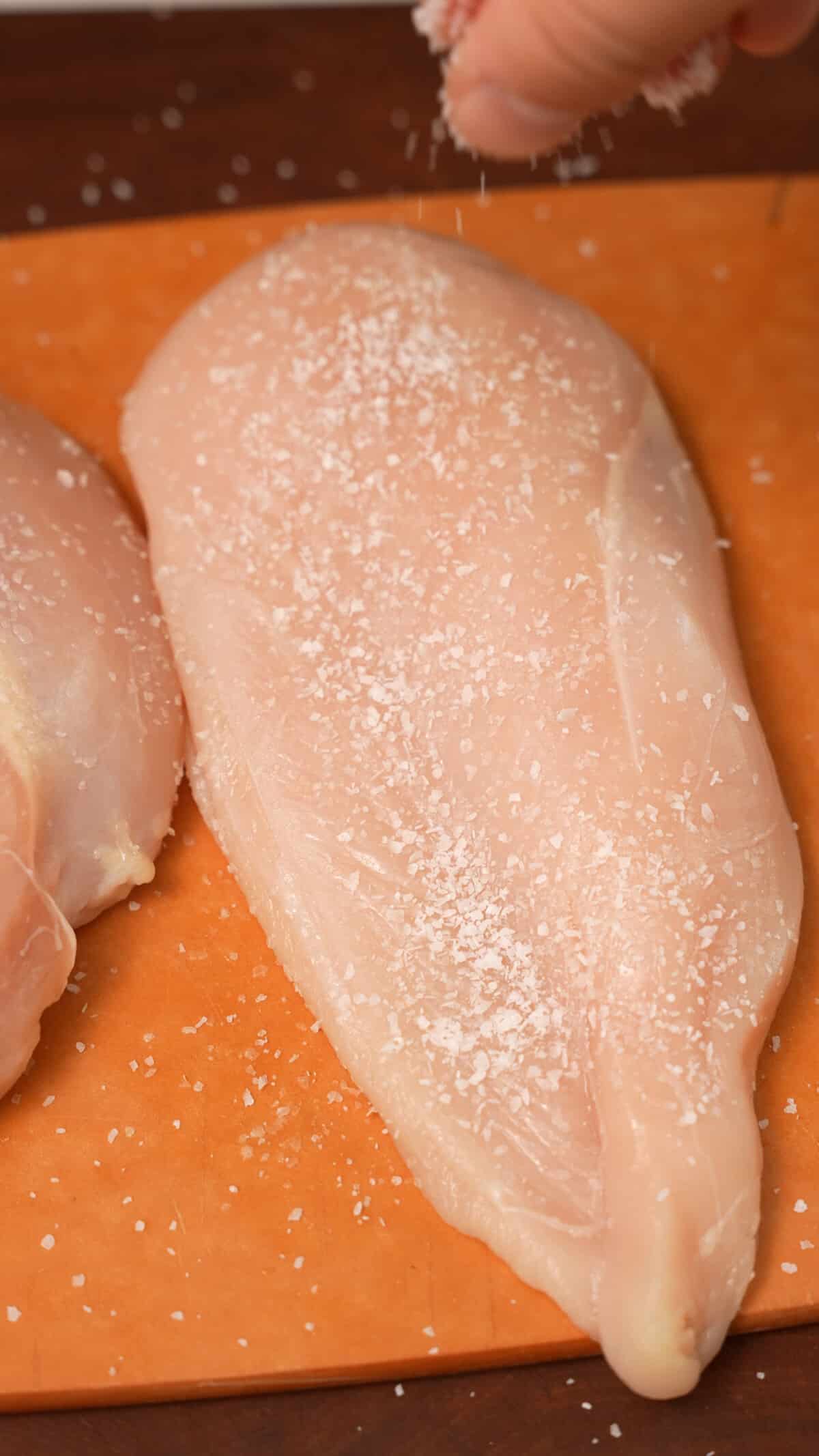 Salt being added to chicken breasts to dry brine.