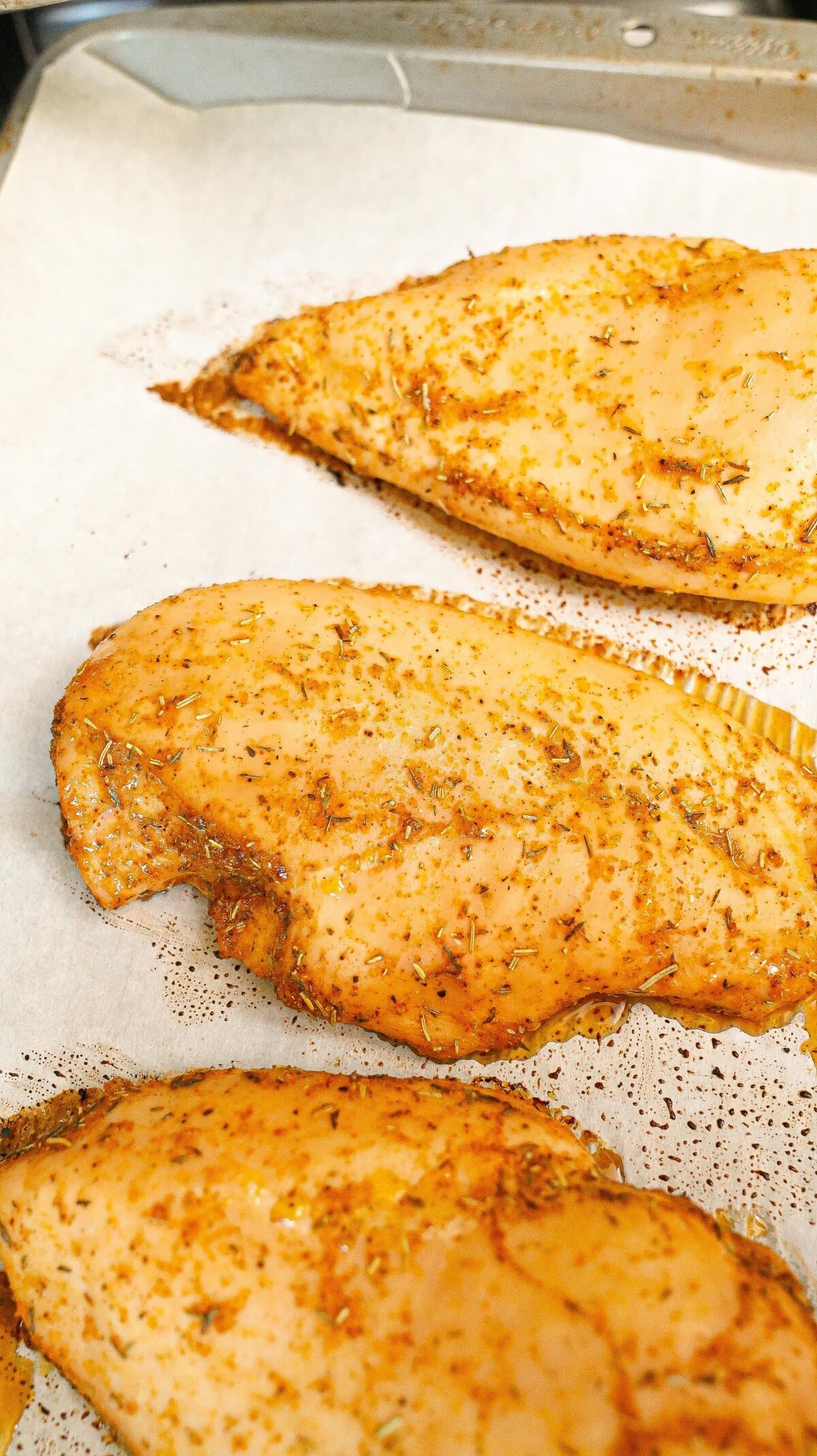 Baked chicken breasts cooked on a tray.