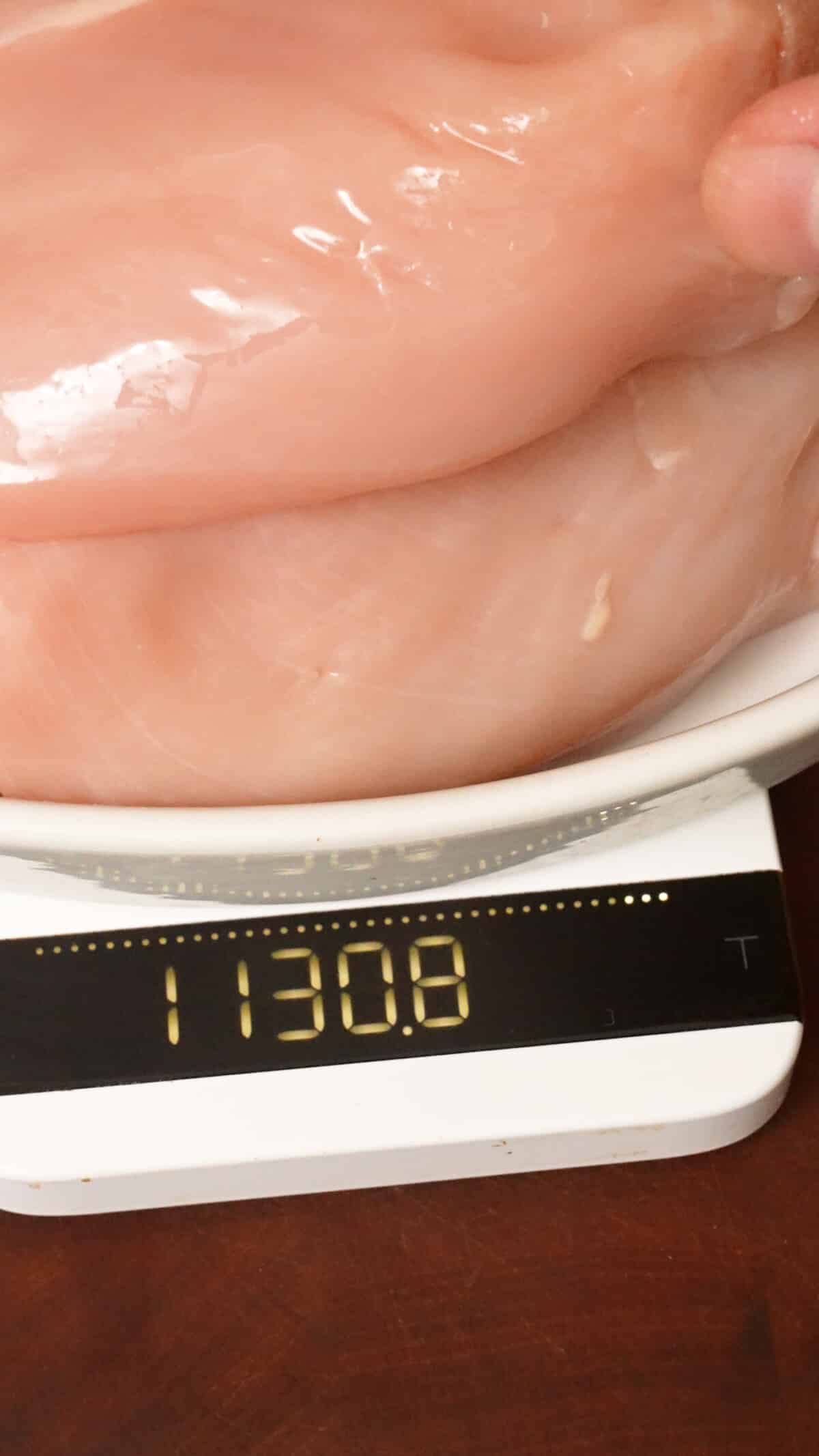 Chicken breasts on a plate showing 1,130 grams.