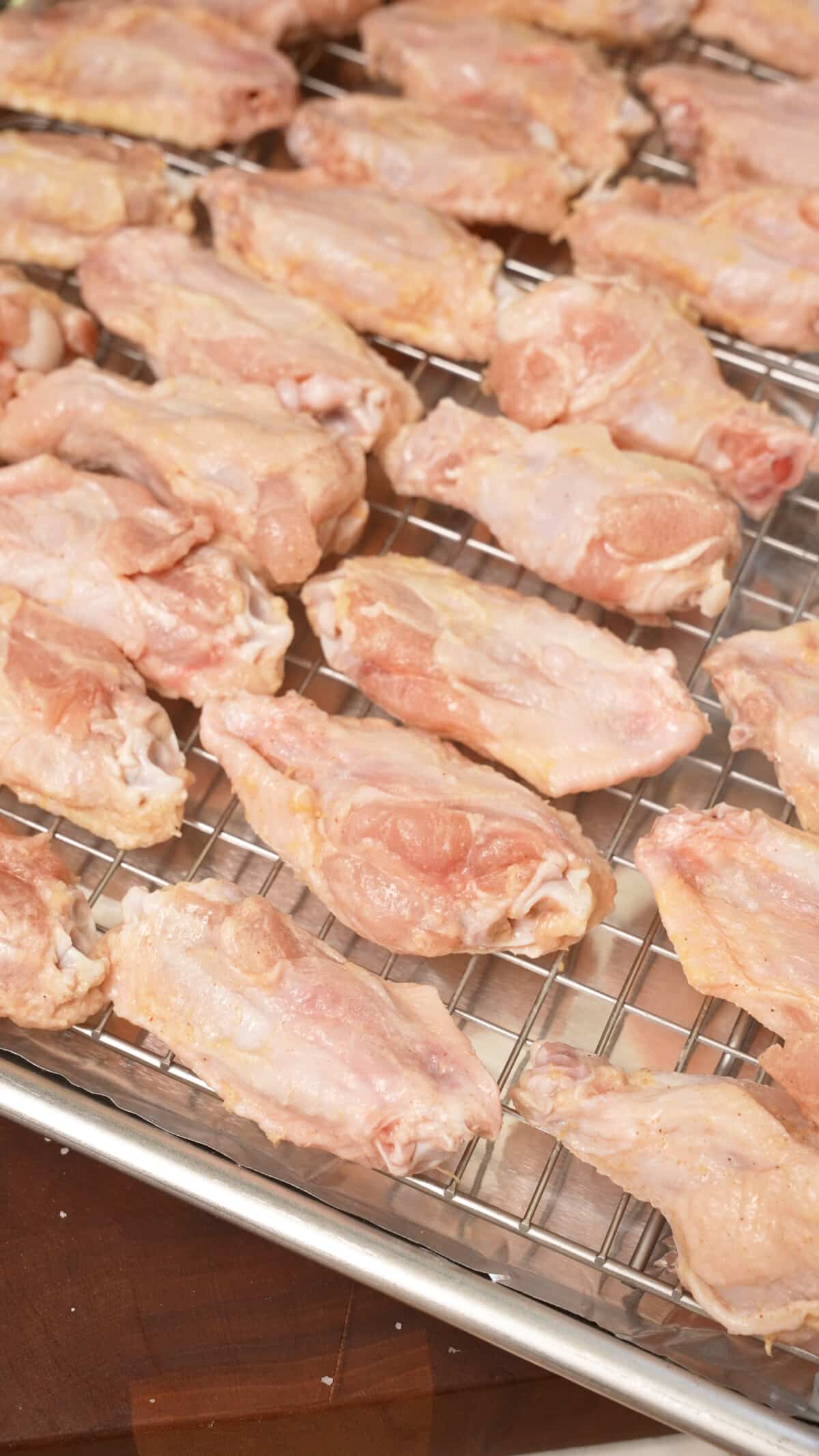 Raw chicken wings on a wire rack before baking.