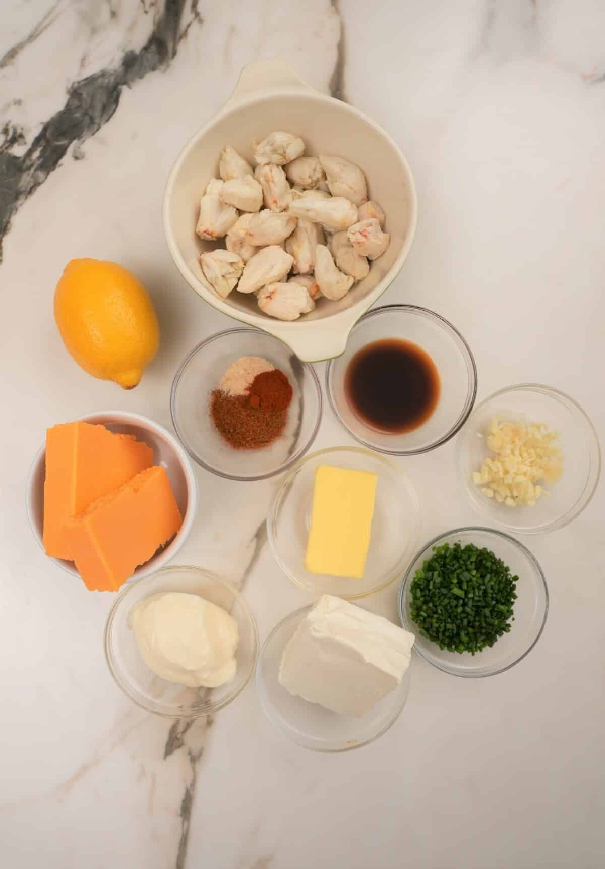 Raw ingredients for baked crab dip in bowls on a table.