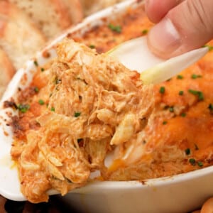 A hand scooping Baked Crab Dip with a lettuce cup.