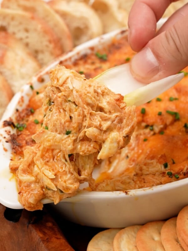 A hand scooping Baked Crab Dip with a lettuce cup.