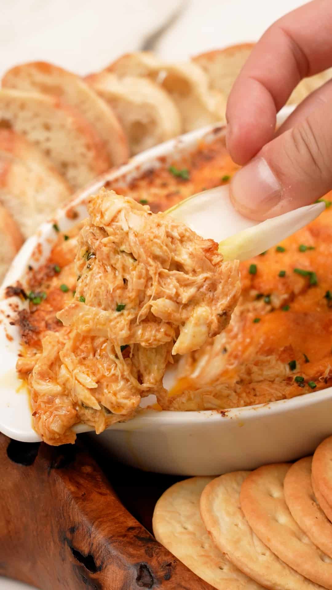 A hand scooping Baked Crab Dip with a lettuce cup.