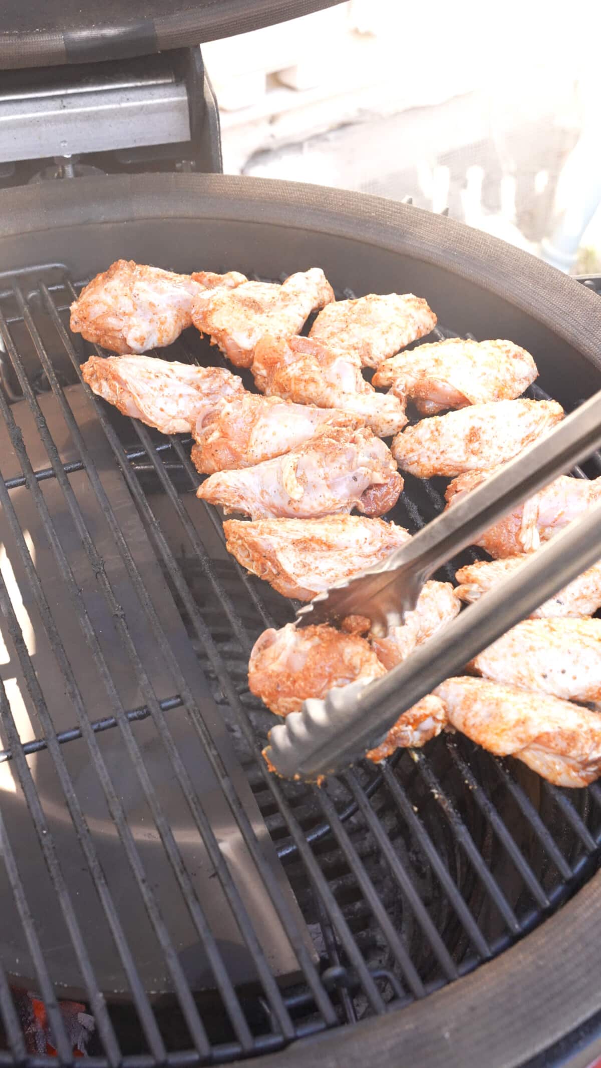 Adding raw chicken wings to the indirect side of the grill.