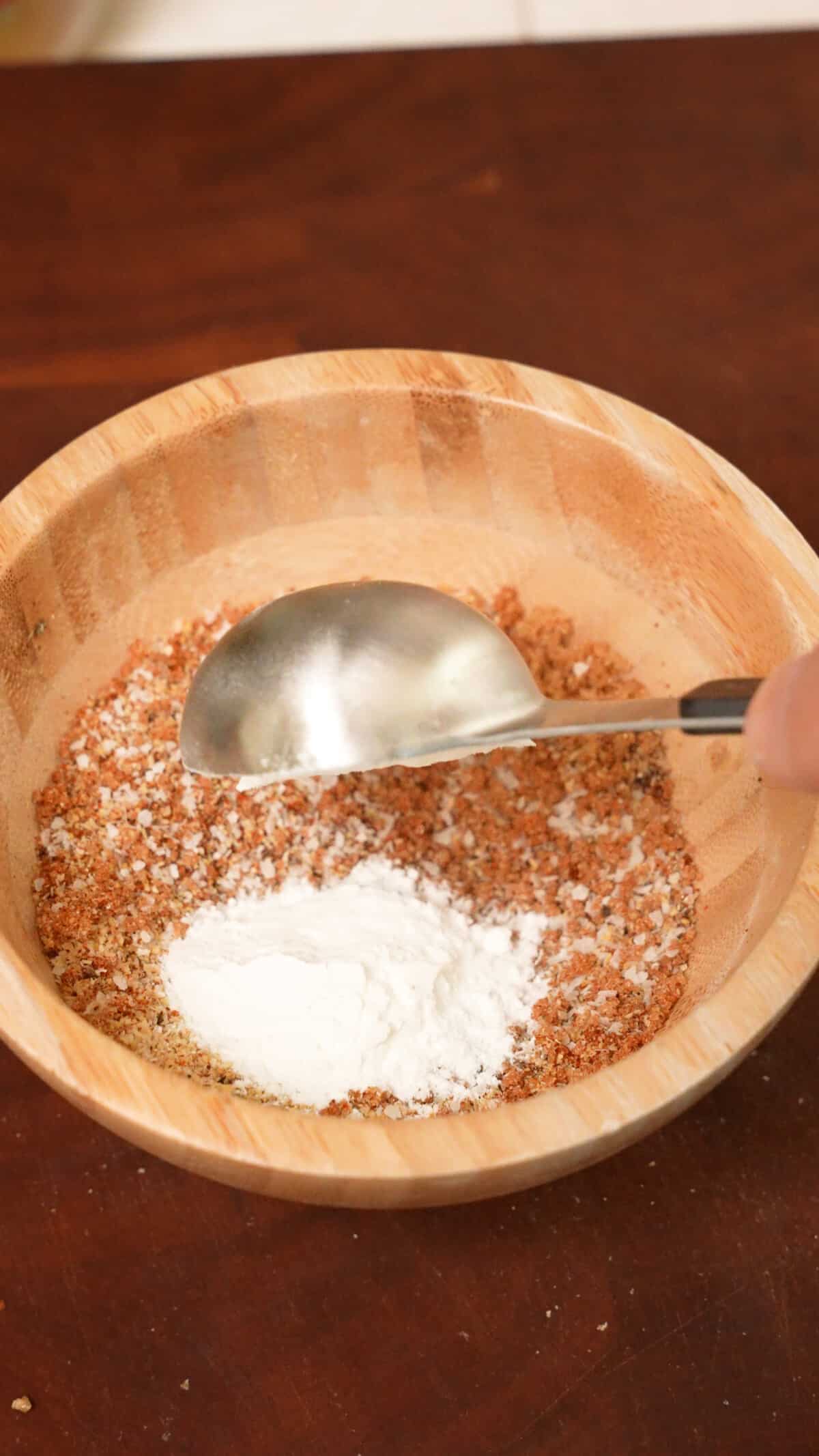 Dry seasonings and baking powder in a wooden bowl to season grilled chicken wings.