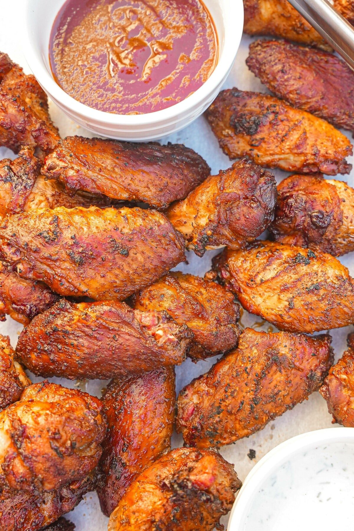 Grilled chicken wings on a tray with BBQ sauce and ranch dressing.