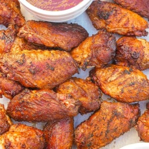 Grilled chicken wings on a tray with BBQ sauce and ranch dressing.