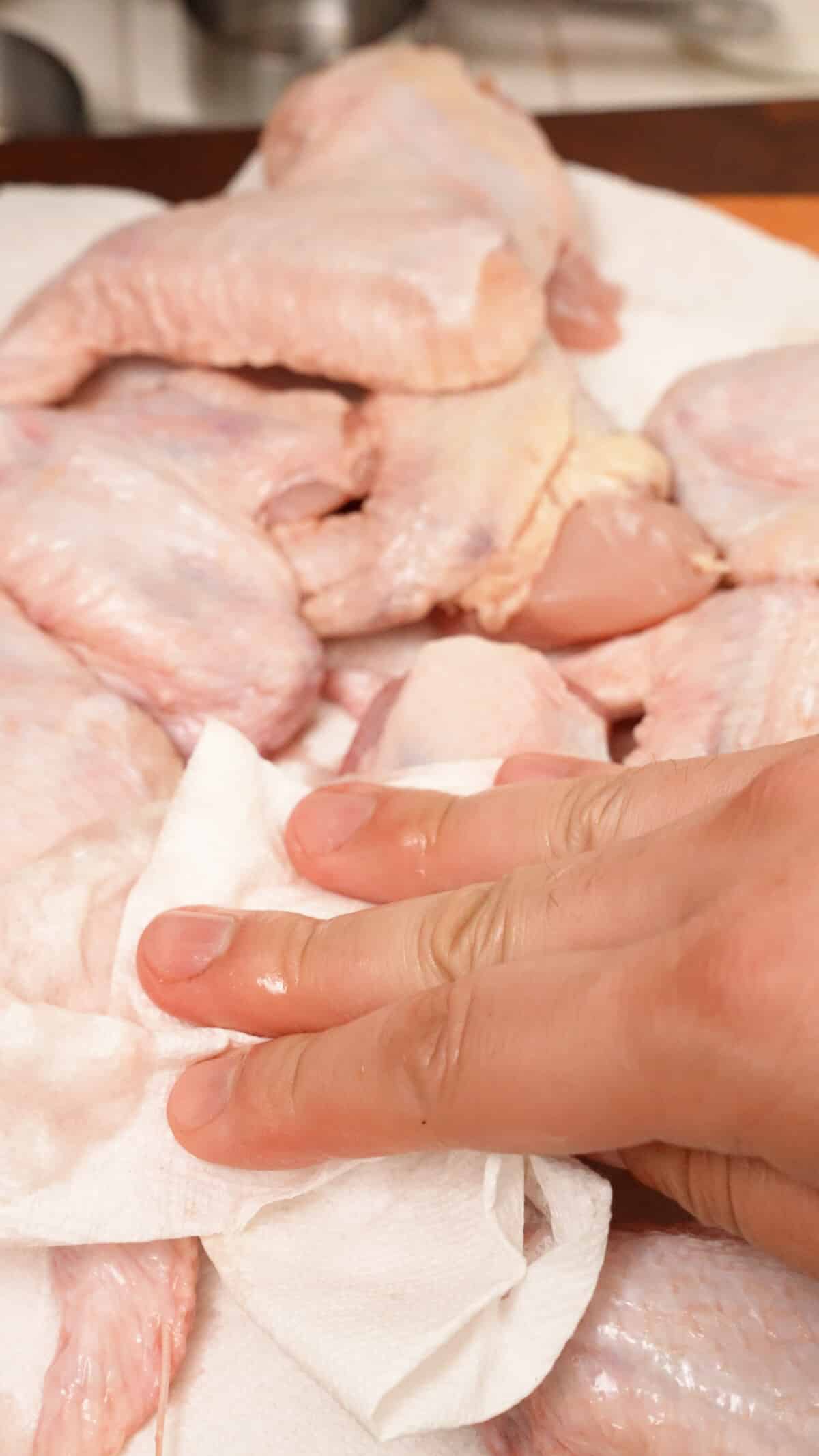 Patting chicken wings dry with a paper towel.