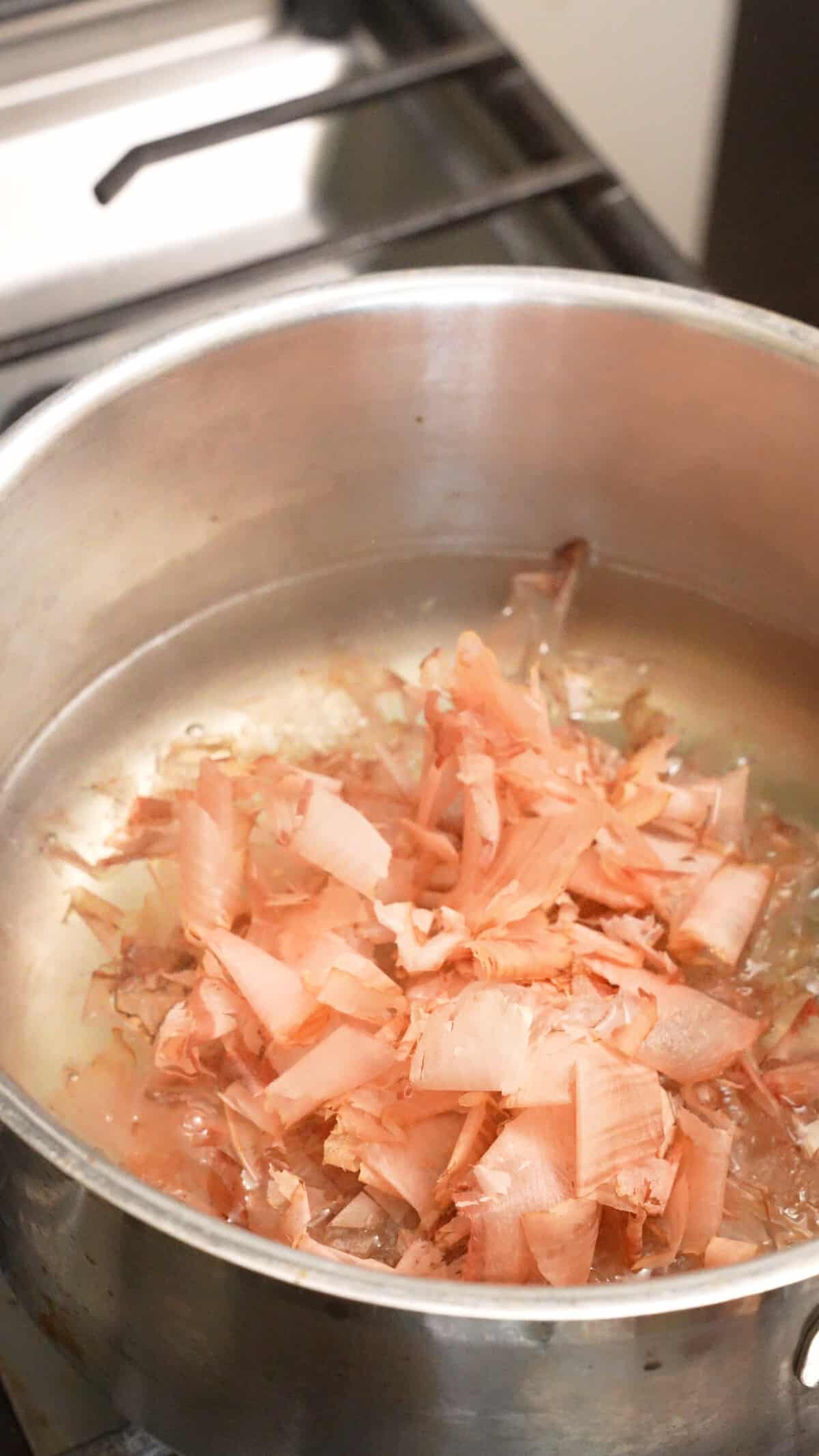 Dry bonito flakes in dashi broth in a pot.