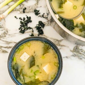 Miso soup in a bowl with seaweed, tofu, dashi stock and scallions.