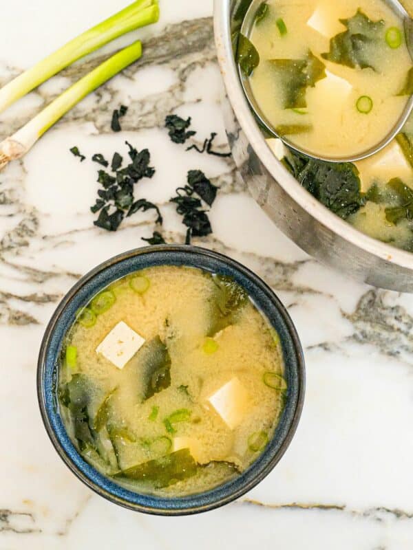 Miso soup in a bowl with seaweed, tofu, dashi stock and scallions.