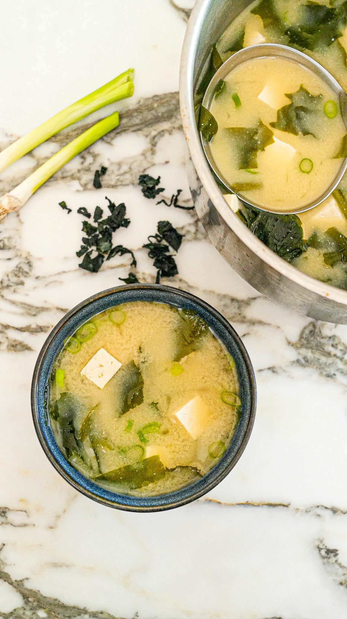 Miso soup in a bowl with seaweed, tofu, dashi stock and scallions.