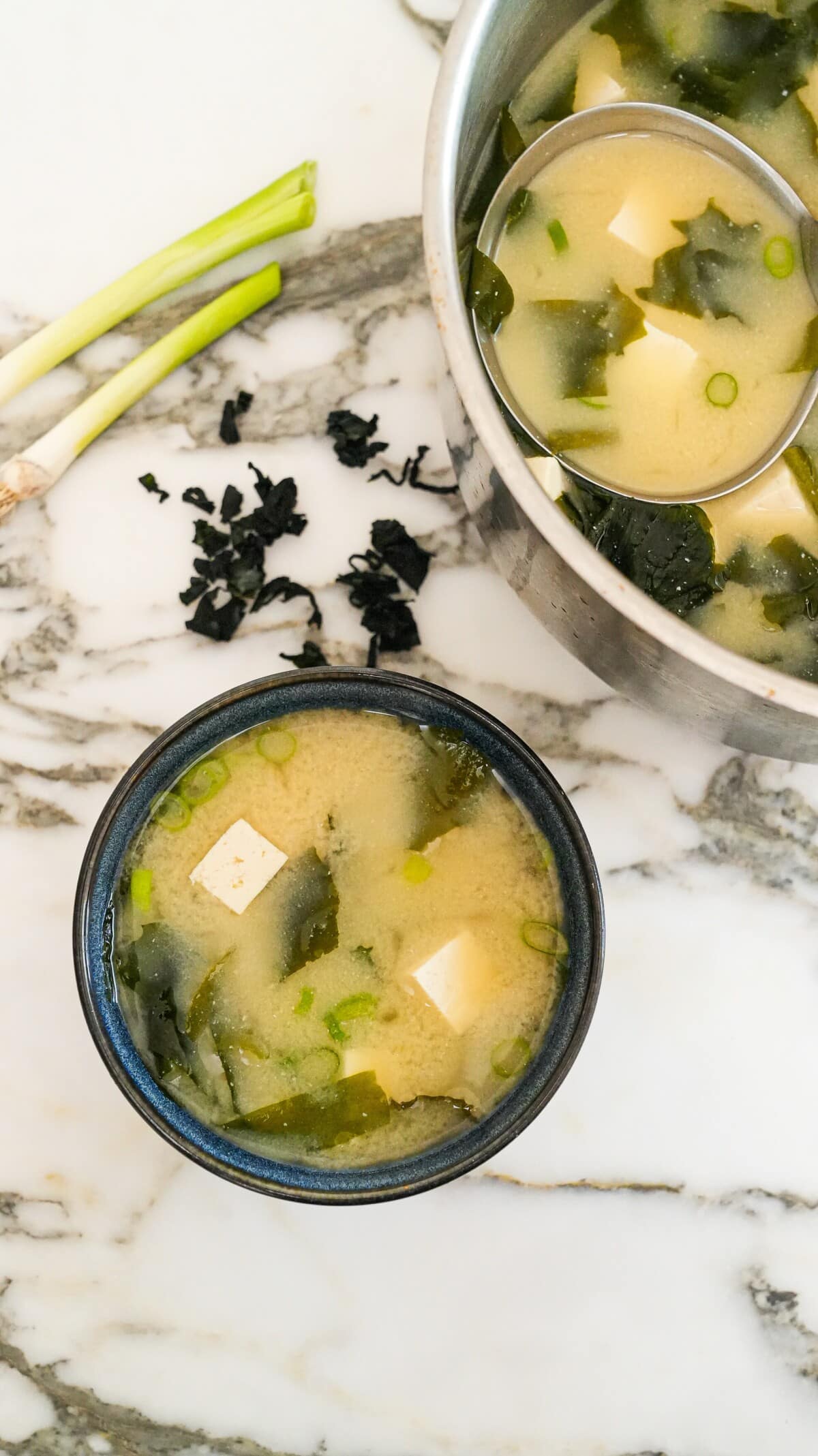 Miso soup in a bowl next to a pot with soup.