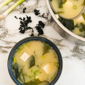 Miso soup in a bowl next to a pot with soup.