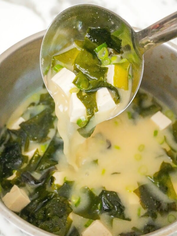 A ladle pouring miso soup in a pot.