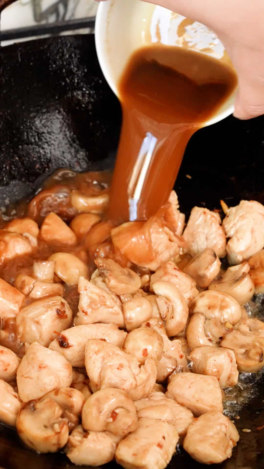 Adding mushroom chicken sauce in a wok.