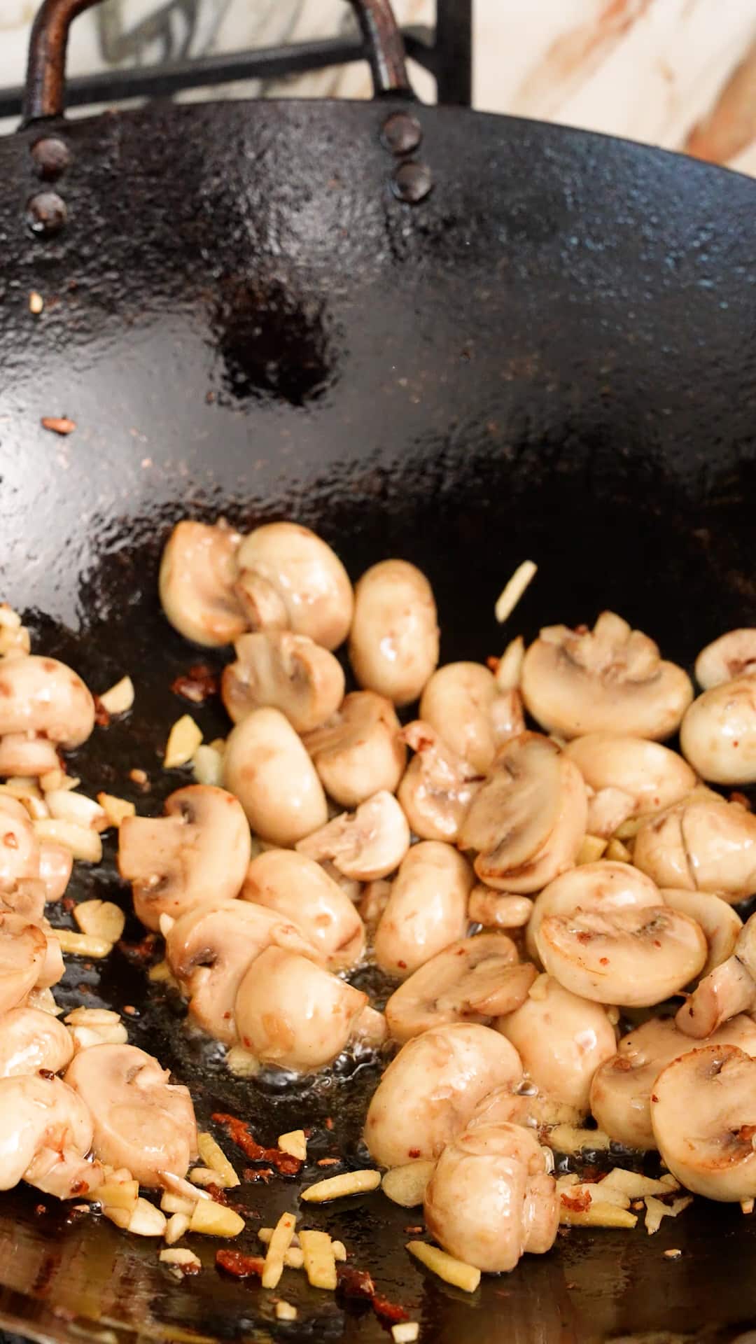 Stir frying mushrooms, ginger and garlic in a wok.