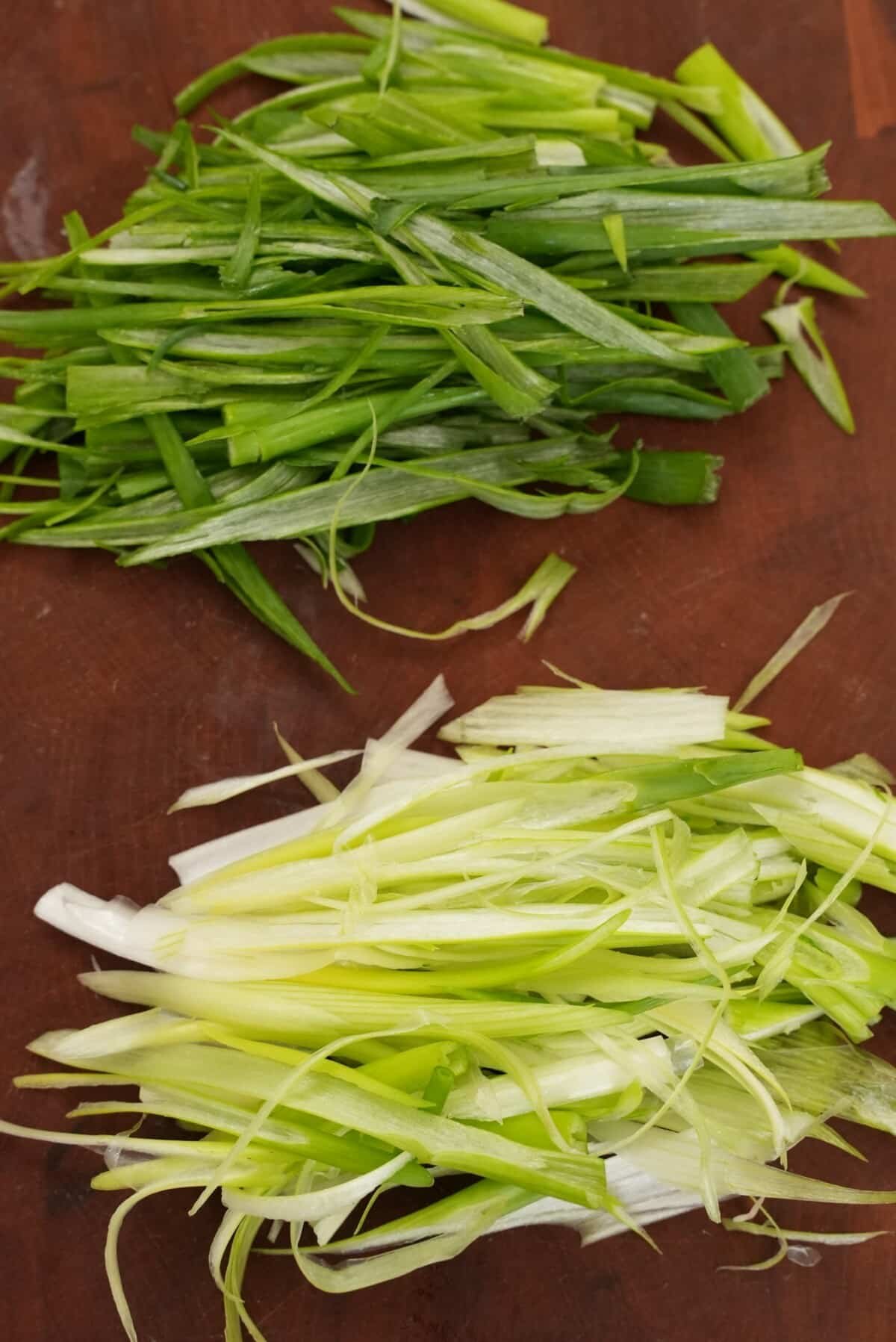 Scallion whites and scallion greens julienned on a cutting board.