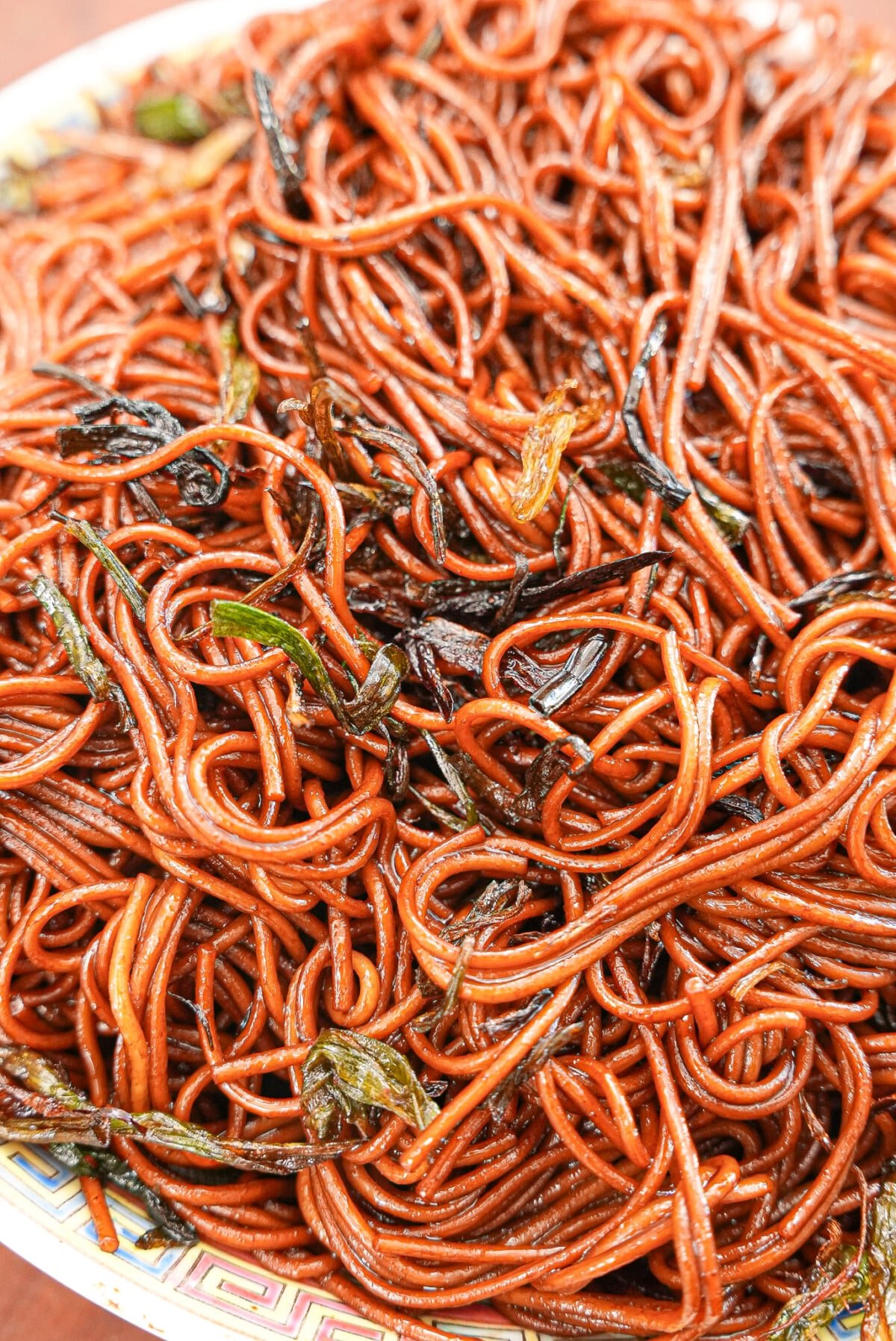 Scallion oil noodles plated on a Chinese ceramic plate.