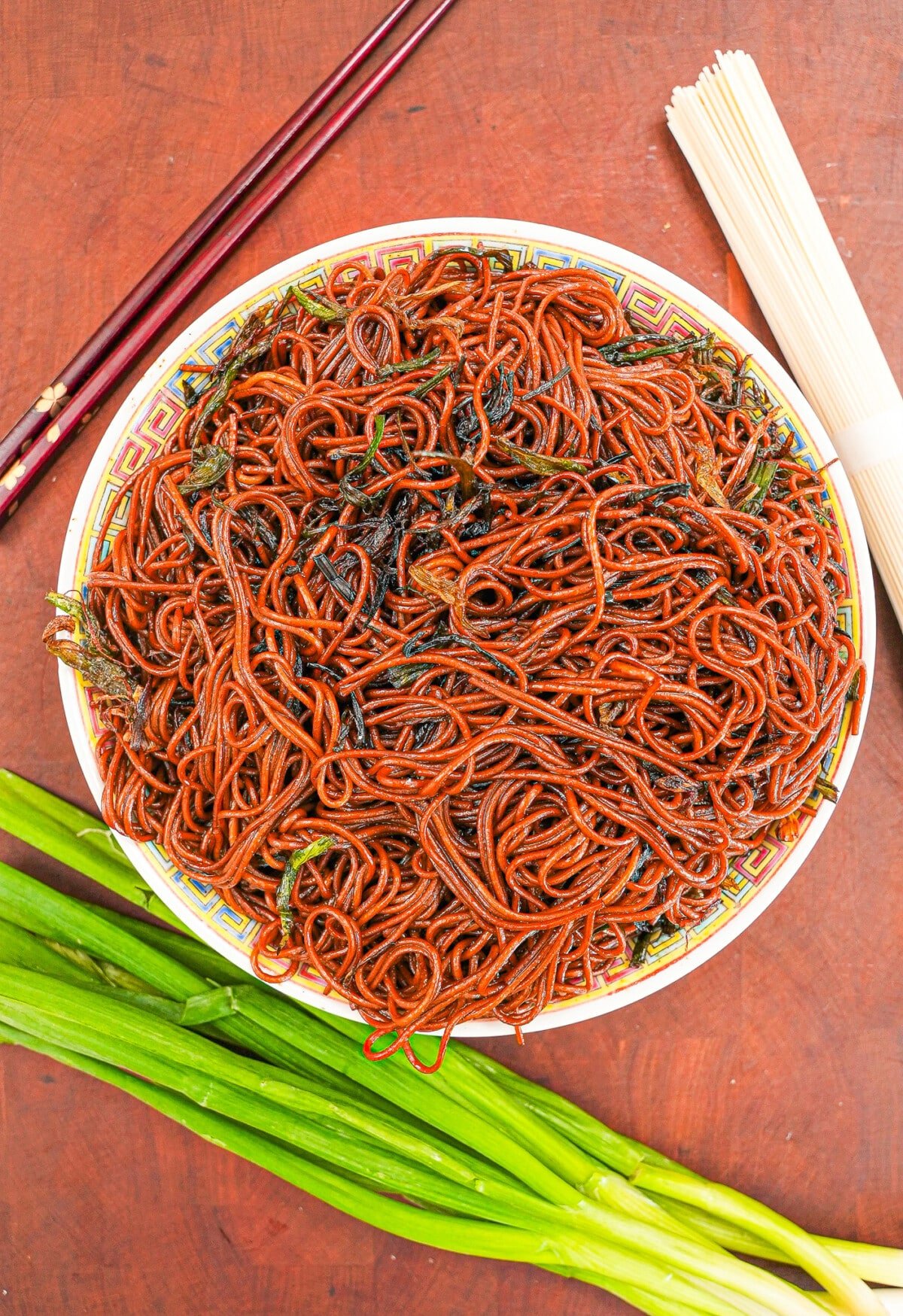 Scallion oil noodles on a plate next to chopsticks.