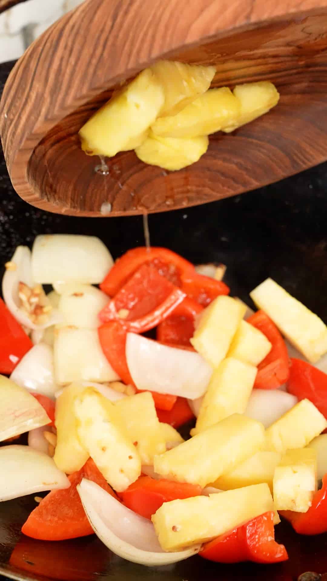 Pineapple being added to the wok.