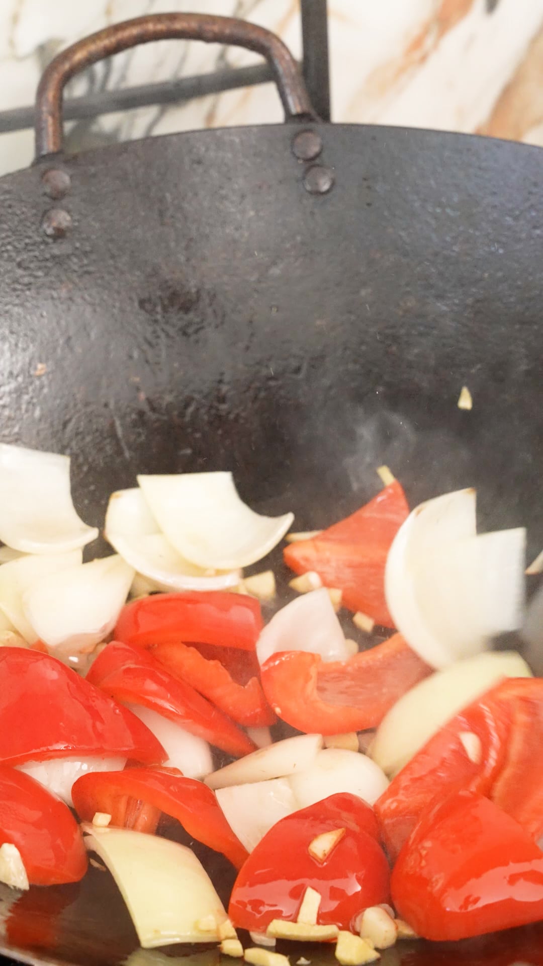 Peppers and onions stir frying in a wok.