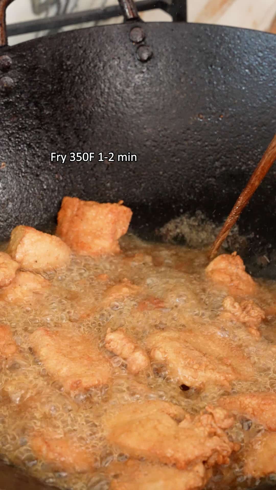 Chicken pieces double frying in oil in a wok.