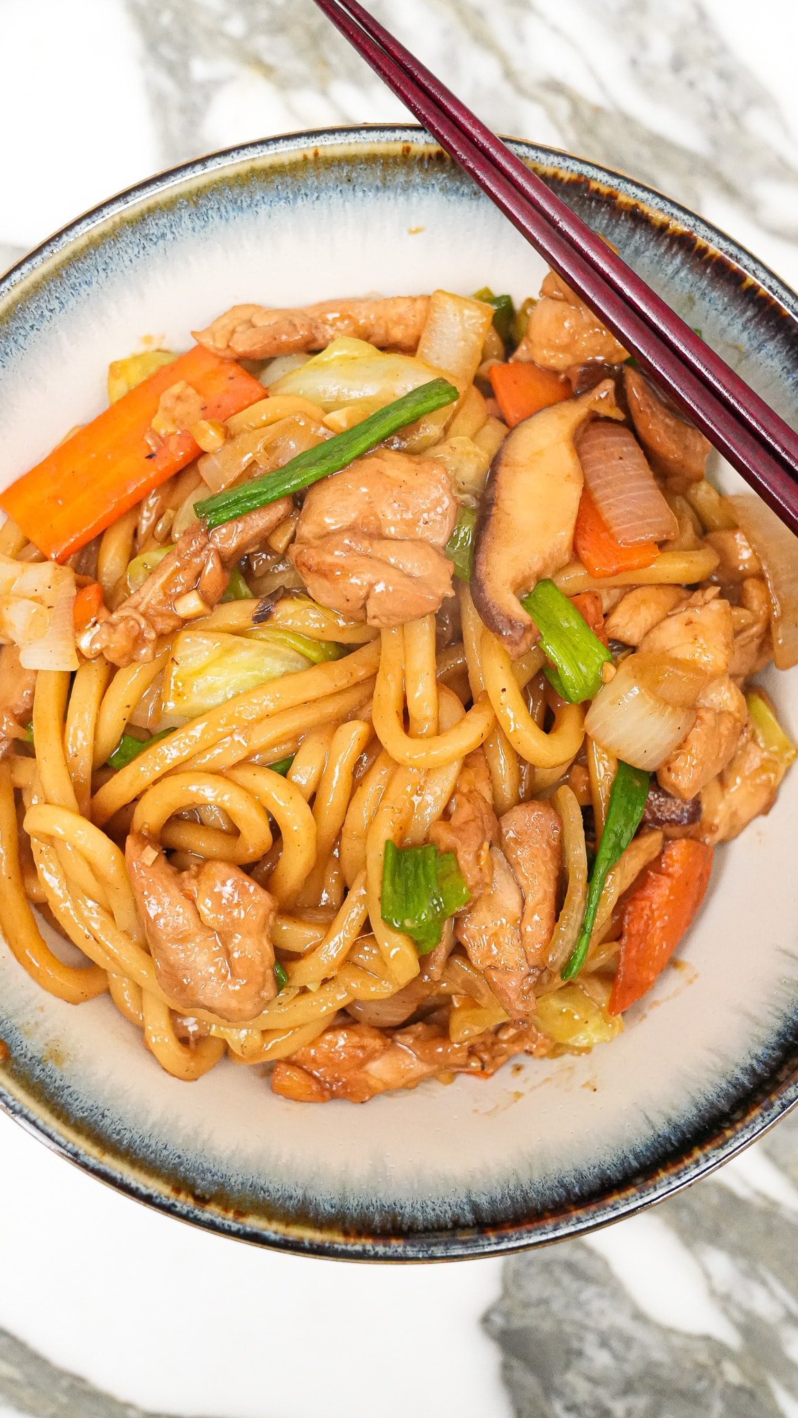 Yaki Udon in a bowl with a pair of chopsticks.