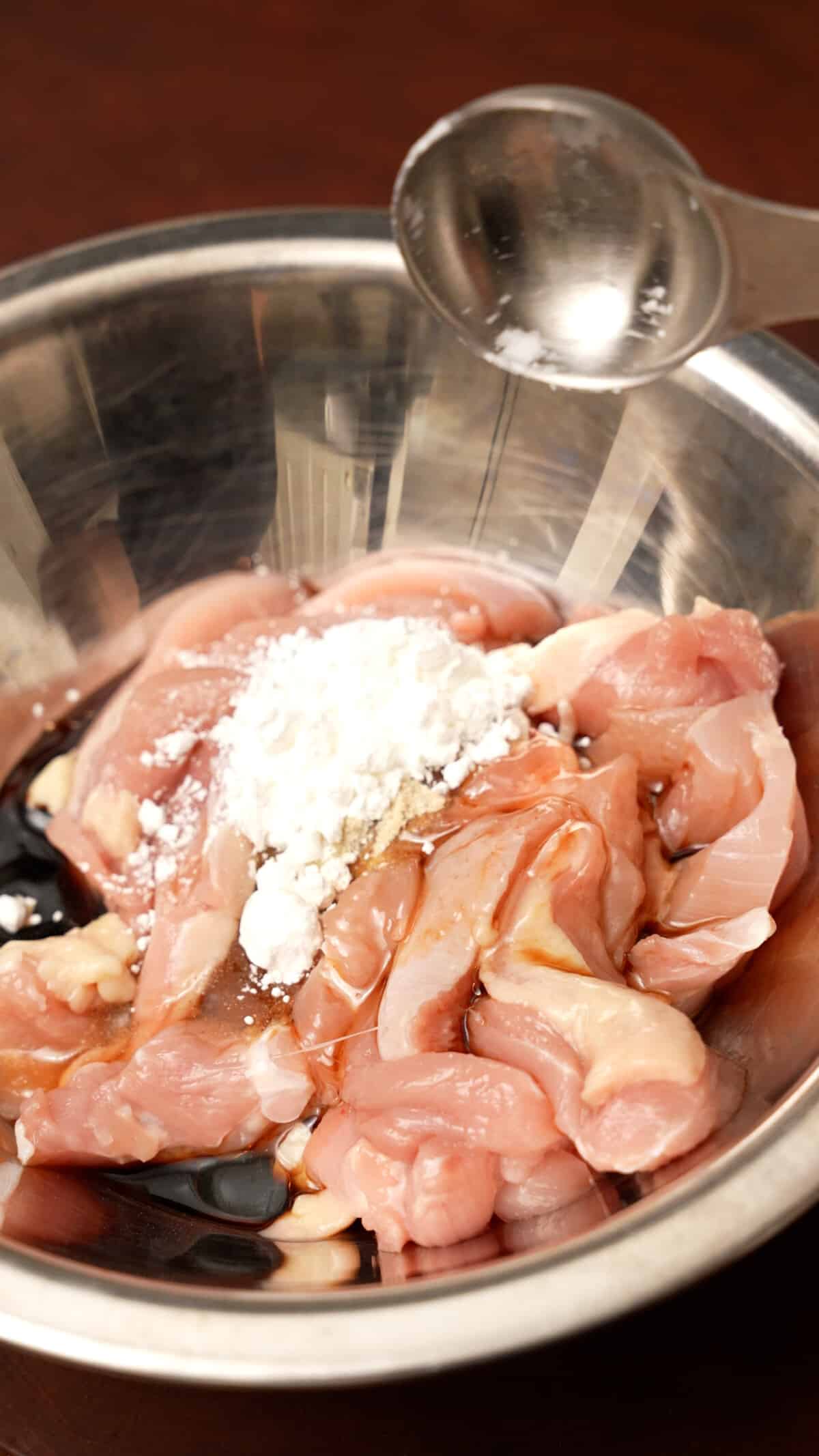 Sliced chicken marinating in a bowl.