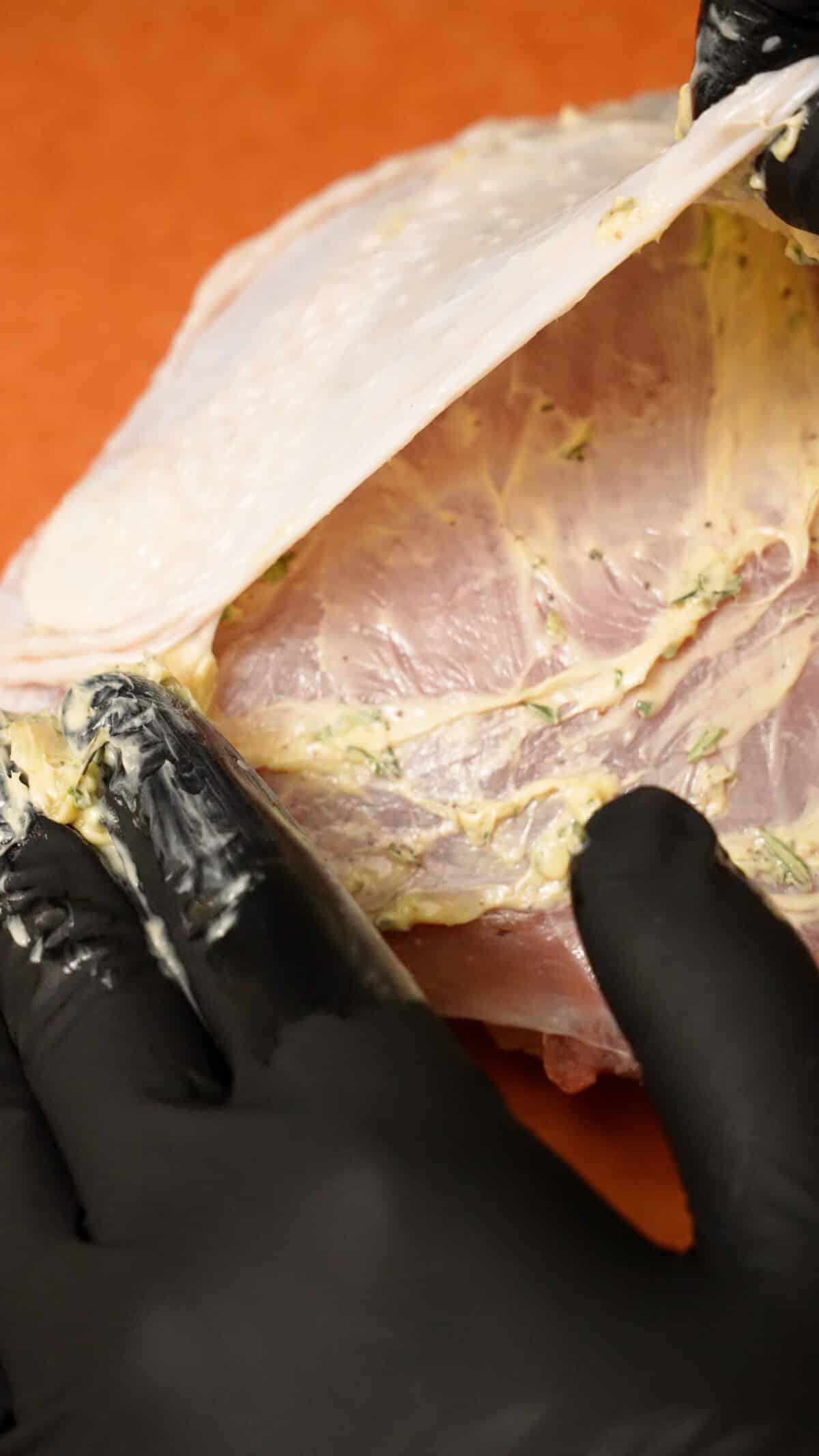 Adding compound herb butter to the turkey breast underneath the skin.