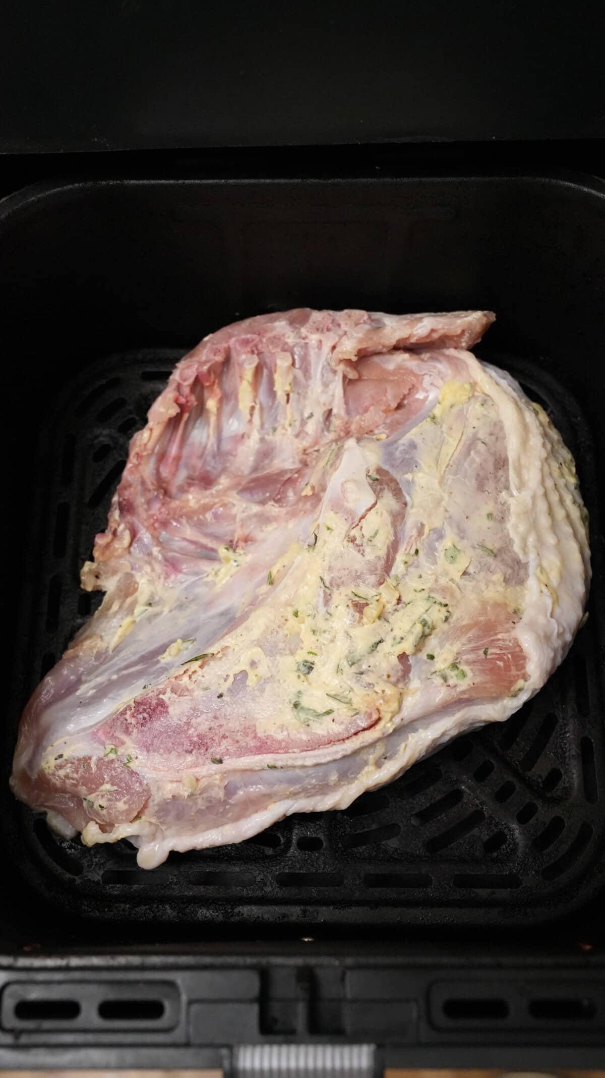 A seasoned turkey breast skin side down in an air fryer.