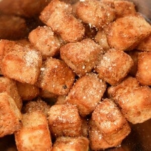 Dry seasoning being sprinkled onto crispy tofu cubes.