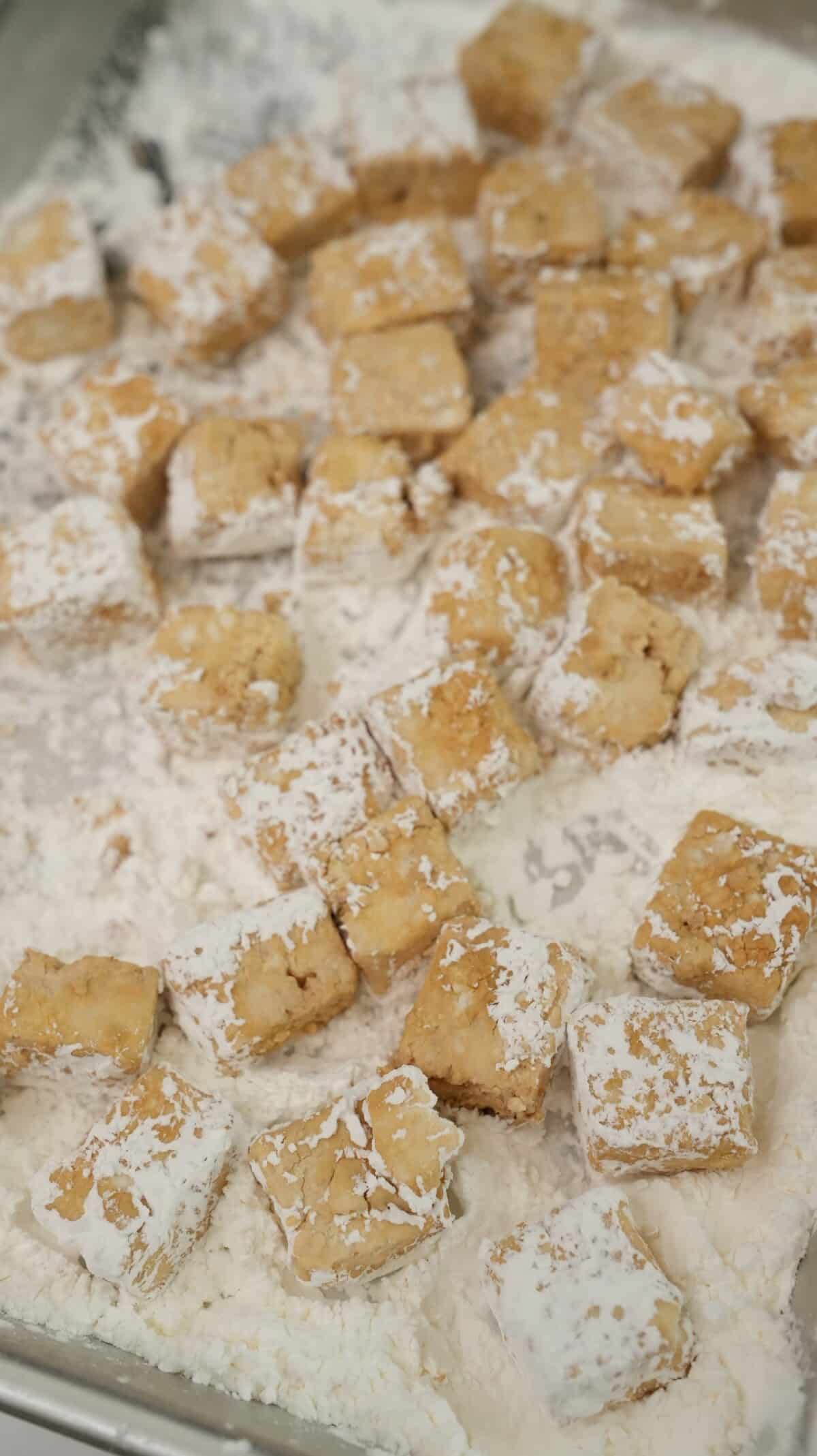 Tofu pieces being dredged in cornstarch and baking powder.