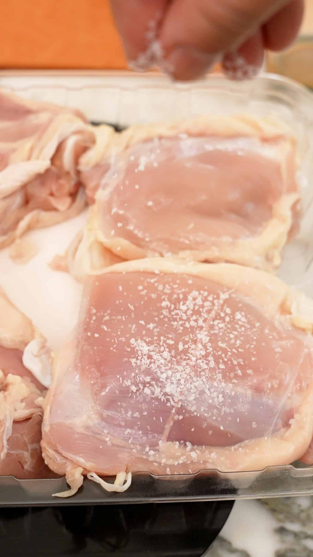 Chicken thigh meat being dry brined with kosher salt.