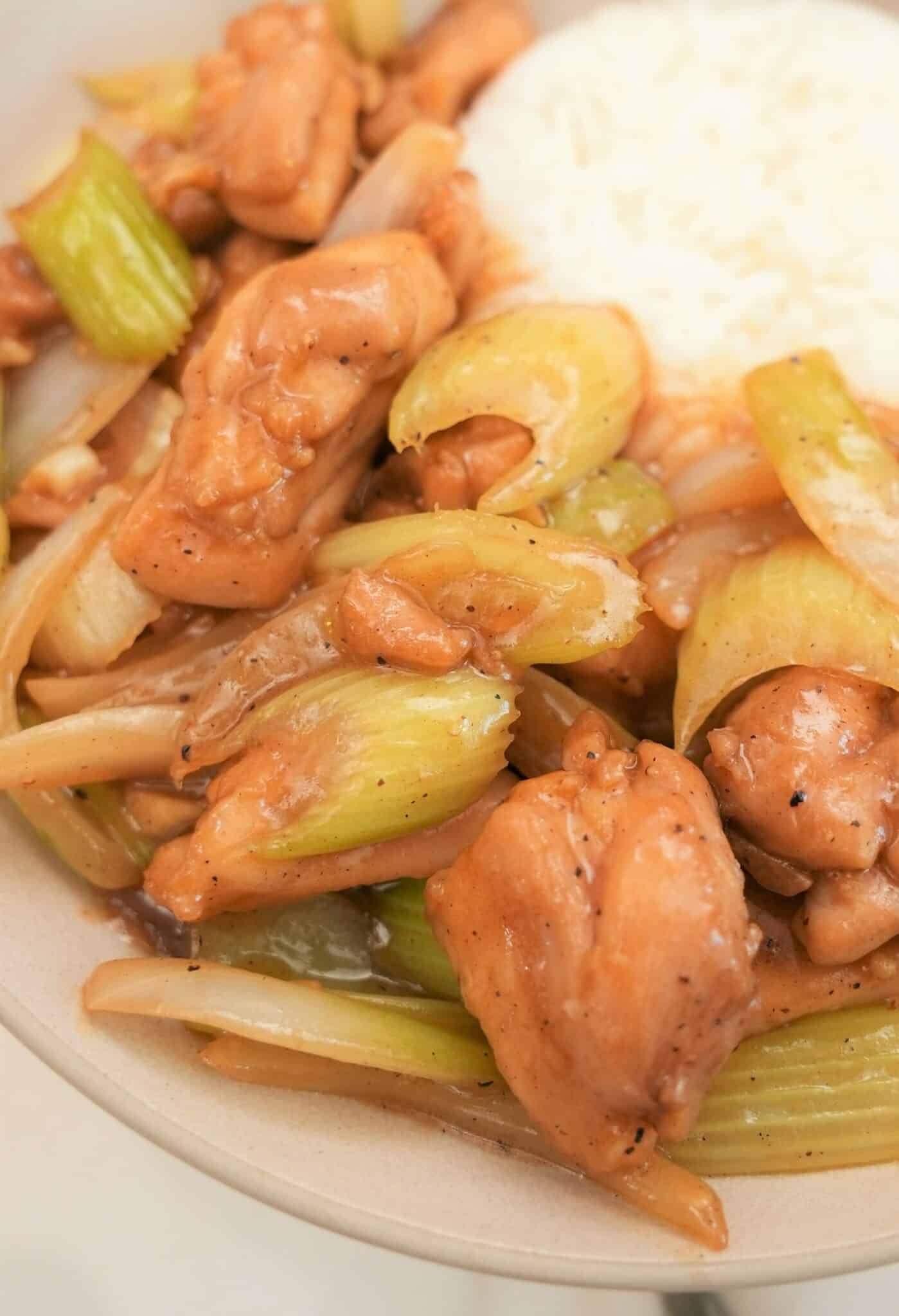 Black pepper chicken in a bowl with rice and chopsticks.