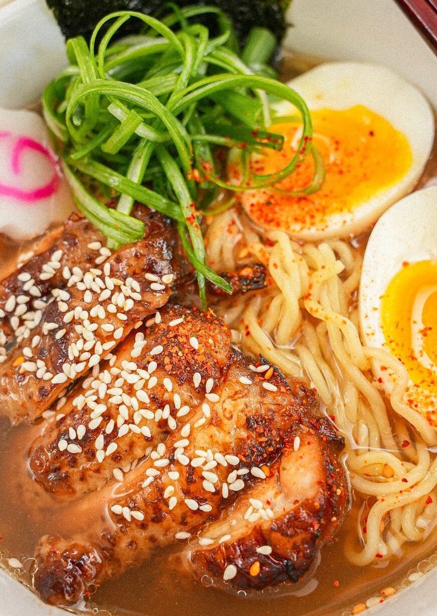 Chicken ramen in a bowl with egg, scallions, fish cakes, and nori.